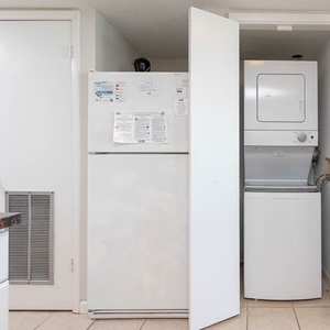 The kitchen area features a convenient stacked washer and dryer, along with a white refrigerator and granite countertops