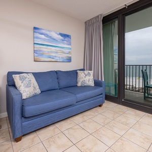 Unwind on the comfortable blue sofa and views of your beachfront balcony through large glass doors