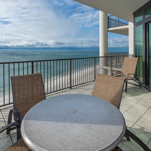 This balcony features a round table and chairs, perfect for enjoying beachfront views and relaxing moments