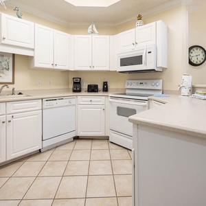 Prepare meals in this kitchen with white cabinetry and appliances, and spacious countertops