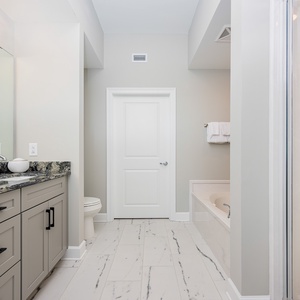 Spacious master bath featuring a stylish vanity, elegant countertops, relaxing jetted tub, and walk-in shower