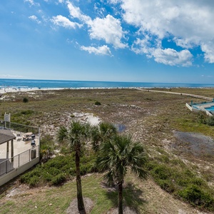 Expansive view of the beach with white sand, the pool area, and a boardwalk leading directly to the shoreline