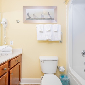 Refreshing guest bathroom featuring a clean tub/shower combo, fresh towels, and a charming nautical-themed artwork