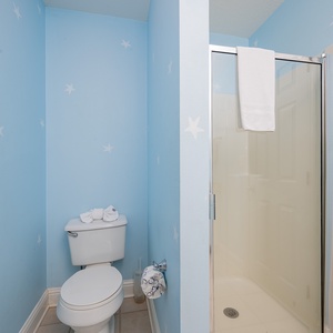 The guest bathroom features cheerful blue walls with star accents, a clean shower, and fresh towels for a delightful stay