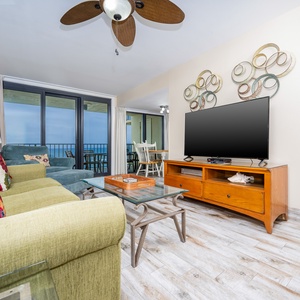 Bright living room featuring colorful seating, a queen sofa-sleeper, a large TV, and stunning views from the balcony
