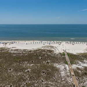 Stunning view of the beach featuring white sand and colorful umbrellas, with a wooden walkway leading to the shore