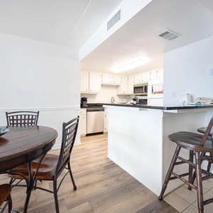 This dining area features a round wooden table and opens to a well-equipped kitchen, perfect for family meals