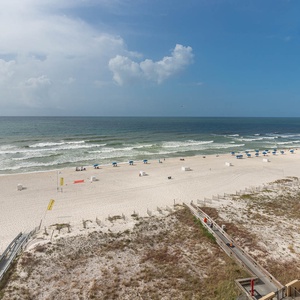Expansive beachfront view featuring white sand and blue umbrellas lining the shore, inviting relaxation and seaside enjoyment