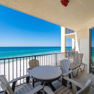 Relax on the balcony with a table and chairs, overlooking the white sand beach and tranquil waters