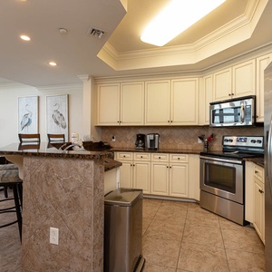 The kitchen features stainless appliances, granite countertops, and a cozy bar area, with a Keurig and a coffee maker