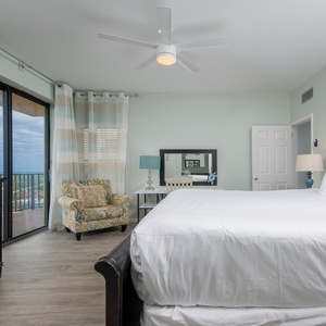 The master bedroom features a cozy atmosphere with a king bed, a stylish armchair, and a balcony offering a lovely view