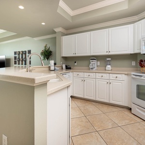 Prepare meals in this kitchen with sleek cabinetry, white appliances, and spacious countertops