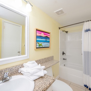 Cool tiled floor and granite countertop brighten the bathroom where you refresh after beach adventures