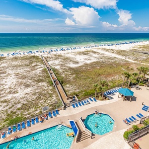 Relax by the pool area surrounded by lounge chairs, with easy access to the beach and vibrant outdoor activities