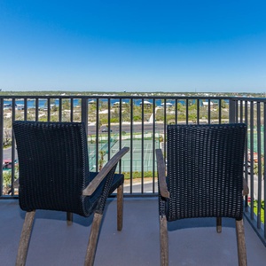 Master balcony seating offers a serene view of the marina and tennis courts, perfect for relaxing in the sun