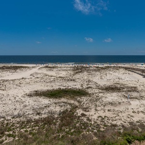 This stunning beach view showcases soft sand dunes leading to the water, perfect for a relaxing getaway