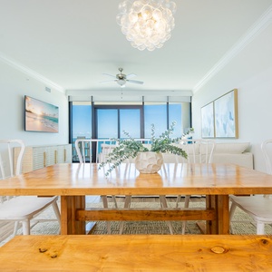 Gather around the wooden dining table, surrounded by light and airy decor, perfect for shared meals and conversations