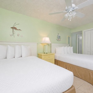Guest suite with two doubles invites restful sleep beneath a gentle ceiling fan and coastal wall art