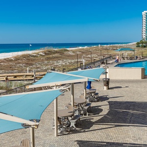 Enjoy relaxing under the shade of umbrellas while taking in views of the beach and the inviting pool area nearby