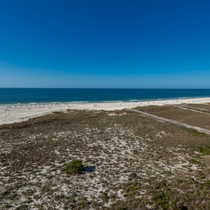 Stunning view of the beach and turquoise gulf waters, framed by sand dunes and wooden walkway
