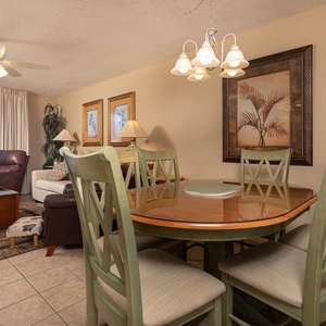 Cozy living space features a round dining table, comfortable seating, and a view of the gulf through large windows