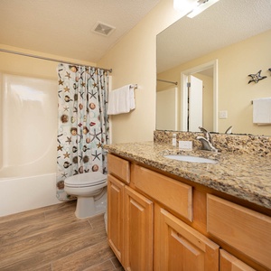Refresh in this guest bathroom featuring a spacious countertop, colorful decor, and a relaxing tub-shower for unwinding