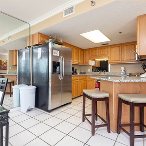 Bright kitchen area featuring wooden cabinetry, granite countertops, stainless appliances, and a breakfast bar
