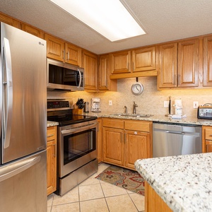 Wood cabinetry complements the granite countertops in this kitchen, featuring sleek stainless appliances and a coffee maker