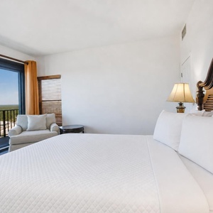 Comfortable master bedroom featuring a king bed, cozy seating area, and beautiful views from large sliding glass doors