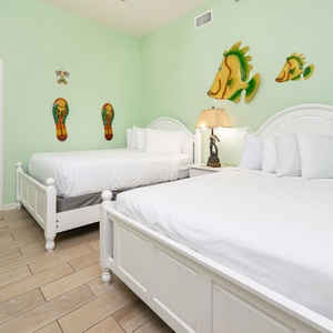 Cheerful guest room featuring two beds, a queen and a double, beach decor, and a cozy atmosphere