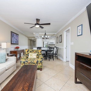 This inviting living area features a comfortable sofa, a mounted TV, and a view of the modern kitchen, perfect for relaxation