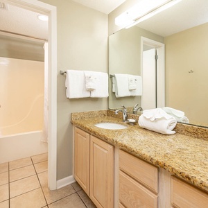 Experience convenience in this master bath featuring a spacious vanity, ample towels, and a relaxing tub-shower
