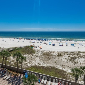 Bask in the vibrant beach scene with colorful umbrellas and gentle waves, just steps from your relaxing getaway