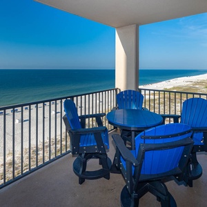 Relax at the outdoor table surrounded by blue chairs, taking in the breathtaking views of the tranquil waters and shoreline