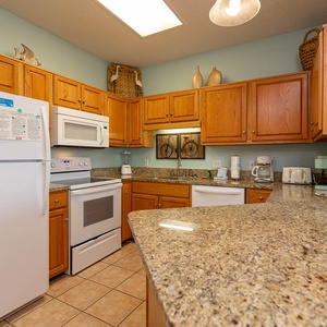 Wooden cabinetry complements the granite countertops in this kitchen, featuring a breakfast bar and white appliances