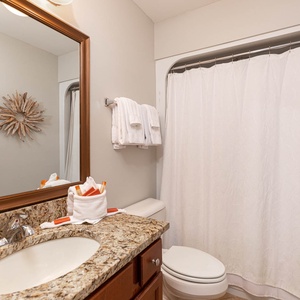 This bathroom features a stylish granite countertop, a large mirror, and elegant decor, creating a refreshing retreat