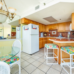 The kitchen features warm wooden cabinetry, a colorful tiled backsplash, and a convenient layout for meal preparation