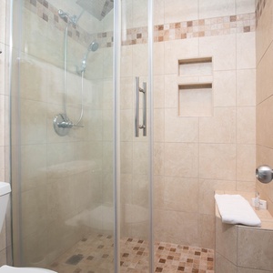 The master bathroom features a walk-in shower with glass doors, elegant tile work, and a small bench for convenience