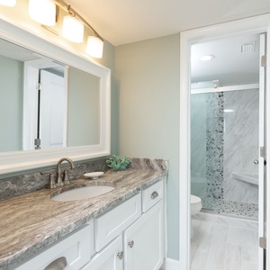 The master bath features a stylish vanity with a marbled countertop, a large mirror, and walk-in shower with decorative tile