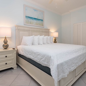 Sink into plush pillows and unwind under coastal art in this king master suite