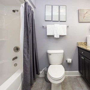 Experience this guest bathroom featuring a granite countertop, decorative art, and ample towels