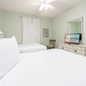 Relax in this cheerful guest bedroom featuring two double beds, a TV, and charming crab decor for a delightful stay
