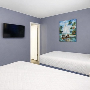 This inviting guest room features two comfortable full beds, a TV, and vibrant art, perfect for a restful stay
