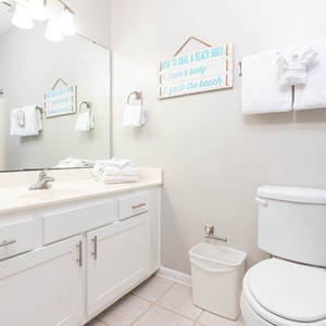 Bright guest bathroom features a spacious vanity, decorative towels, and a vibrant shower curtain, enhancing the beach vibe