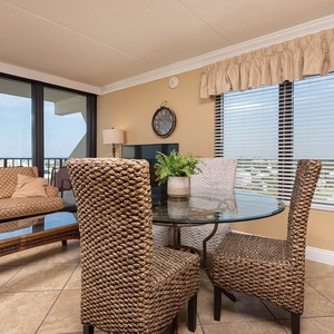 This inviting seating area features a glass table and woven chairs, perfect for enjoying views from large windows