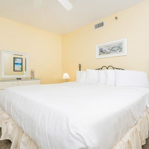Cozy guest bedroom featuring a king bed, a decorative mirror, and soft yellow walls, creating a warm ambiance