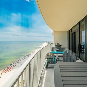 Relax on the balcony enjoying views of the beach and vibrant umbrellas along the shoreline