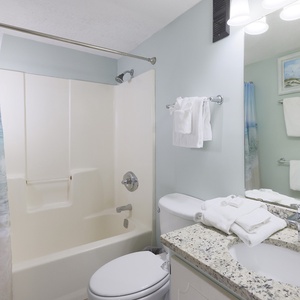 This bathroom features a clean design with a relaxing beach-themed shower curtain and modern fixtures for comfort