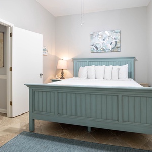 Serene guest bedroom featuring a light blue king bed, plush white pillows, and soft lighting for a restful atmosphere