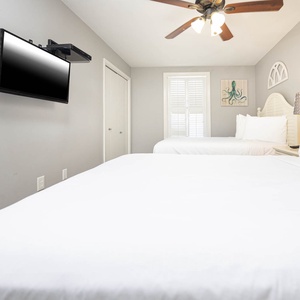 Relax in this guest bedroom featuring two double beds, a flat-screen TV, and charming decor for a restful stay
